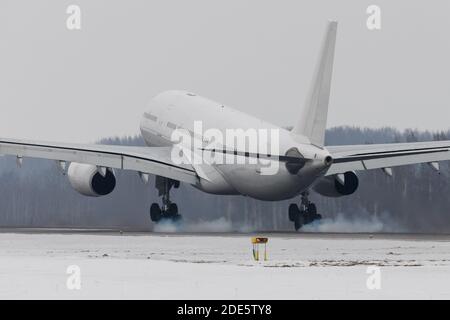 Großkörper-Flugzeug Landung auf Start-und Landebahn mit Rauch von Chassis, Winterzeit. Setzen Sie sich mit Getrieberauch in Berührung. Luftfahrt, Transportkonzept Stockfoto