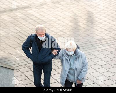 Ältere Frau und Mann tragen schützende Gesichtsmasken, gehen Arm in Arm zusammen während COVID-19 epidemic.Istanbul, Türkei. Stockfoto