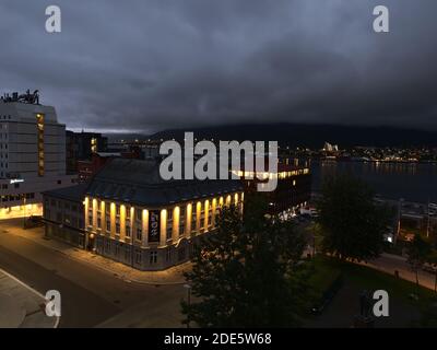 Tromsø, Norwegen - 08-23-2020: Luftaufnahme des Stadtzentrums von Tromsø mit beleuchteten Gebäuden, Tromsøbrua-Brücke sowie Arktischer Kathedrale. Stockfoto