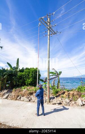 Ein Elektrizitätspersonal arbeitet an einem Strommasten in Tingloy Island vor Batangas, Philippinen Stockfoto