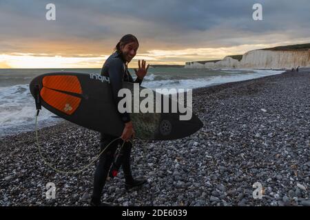 England, East Sussex, Eastbourne, Birling Gap, The Seven Sisters Cliffs and Beach, Male Surfer Walking on Beach mit Surfbrett Stockfoto