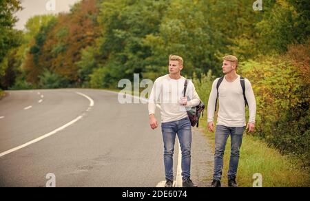 Fahren Sie in der Nähe des Stadtrandes. Reisende auf dem Weg. Freunde, die hitchhitchhamps unterwegs Firmenfreunde Reisende, die auf dem Naturhintergrund der Straße hitchwandern. Beginnen Sie mit dem Wandern ein tolles Abenteuer in Ihrem Leben. Stockfoto