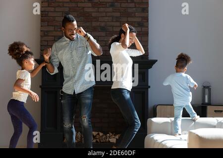 Glückliche afroamerikanische Ehegatten und zwei Kinder tanzen zu Hause Stockfoto