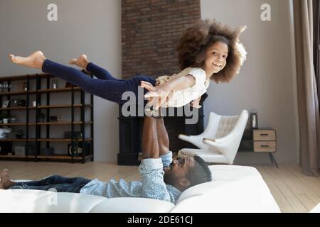 Schwarzer Vater spielt mit Tochter, die sie in den Armen hochhebt Stockfoto