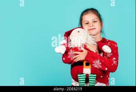 Weihnachtsstimmung Konzept. Weihnachtstraditionen. Lieber Weihnachtsmann. Kleines Kind tragen Santa Spielzeug blauen Hintergrund. Kleines Mädchen Spielzeug vorhanden. Winterurlaub. Geschenk bringt Freude und Glück. frohe weihnachten. Stockfoto