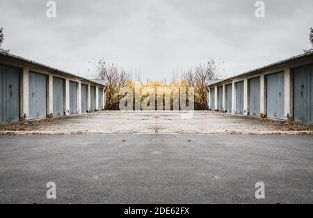 Parkplatz und Garagen an den Seiten mit Vegetation dahinter Der Zaun am bewölkten Tag Stockfoto