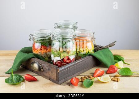 Gesunde vegetarische hausgemachte Mason Jar frischer Salat mit Chickpea, Erdbeere und Gemüse auf Schneidebrett auf einem hellen Hintergrund.Diät, Detox, sauber eati Stockfoto