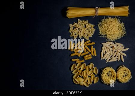 Verschiedene Arten von Pasta auf schwarzem Hintergrund. Ansicht von oben. Verschiedene Formen der Pasta. Kopieren Sie Raum für Design. Stockfoto