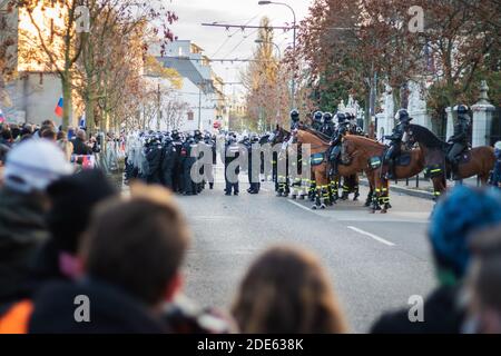 Menschenmenge mit bewaffneten Polizisten auf Pferden dahinter Der Zaun auf slowakische Anti-Regierungs-Demonstration gegen Corona-Virus Einschränkungen Stockfoto