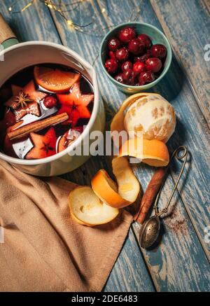 Tischstill-Leben mit Glühweintopan mit Gewürzen, Früchten, Zimtstangen, Orangenschale auf dem rustikalen Tischuntergrund. Weihnachten und Neu Stockfoto