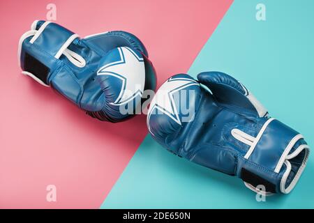 Boxing blaue Handschuhe auf einem rosa und blauen Hintergrund diagonal. Nahaufnahme. Das Konzept des Kampfes und des Siegesstrebens. Stockfoto