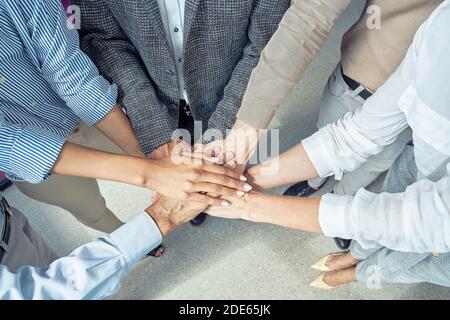 Nahaufnahme von Geschäftsleuten, die ihre Hände zusammenlegen und lächeln, während sie im Büro den Erfolg feiern Stockfoto