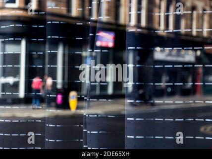 Reflexionen durch ein Schaufenster von Menschen auf den Straßen, Glasgow Stockfoto