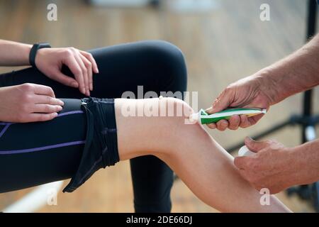 Therapeut Anwendung Salbe Creme auf weibliche Knie. Stockfoto