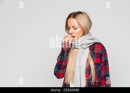 Frau im karierten Hemd, gewickelt Schal husten, geschlossenen Augen. Kranke Frau hat Grippe. Kälte, Krankheit. Stockfoto