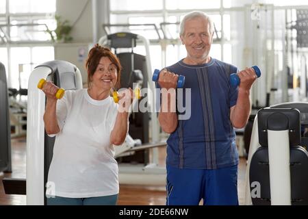 Zufriedenes Seniorenpaar mit Hanteln im Sportverein. Stockfoto