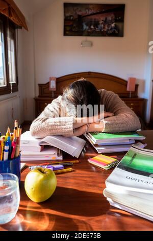 Junge Studentin schläft auf ihrem Schreibtisch im Schlafzimmer und studiert zu Hause. Home-Konzept. Stockfoto