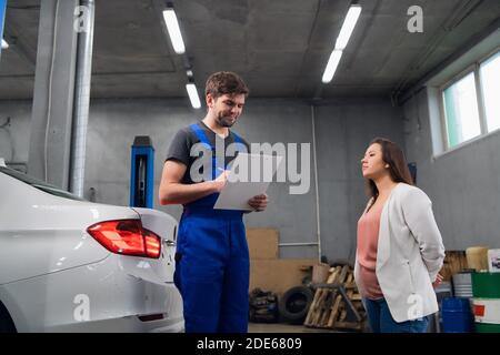 Mechaniker im Gespräch mit einem Kunden über eine Fahrzeugreparatur Stockfoto