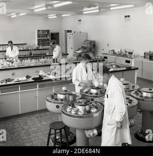 1960er Jahre, historische, männliche Forscher tragen weiße Mäntel, die in einem großen offenen Labor arbeiten und Inhaltsstoffe testen, die bei der Herstellung von chemischen Farbstoffen für die Bekleidungs- oder Bekleidungsindustrie verwendet werden, Leeds, Yorkshire, England, Großbritannien. Stockfoto