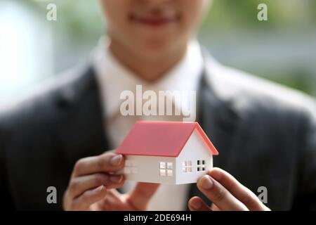 Geschäftsmann hält Modellhaus. Architektur, Bau, Bau, Immobilien und Immobilienkonzept Stockfoto