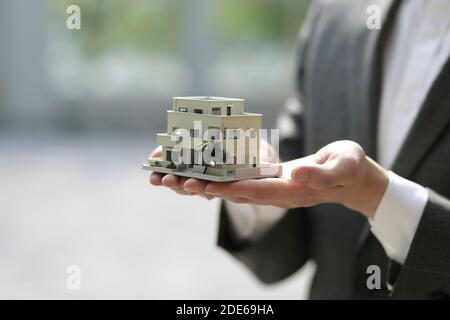 Geschäftsmann hält Modellhaus. Architektur, Bau, Bau, Immobilien und Immobilienkonzept Stockfoto