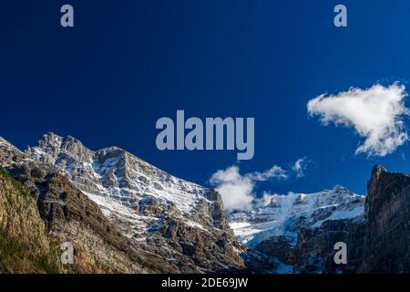 Schneebedeckte majestätische Berggipfel mit dunkelblauem Himmel und fließenden Wolken im Hintergrund. Tal der zehn Zinnen, Moraine See. Banff National Pa Stockfoto