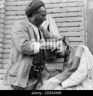 Originalunterschrift: Irak. (Mesopotamien). Bagdad. Ansicht von Straßenszenen und Typen. Straßenbarbier bei der Arbeit - Ort: Irak--Bagdad ca. 1932 Stockfoto