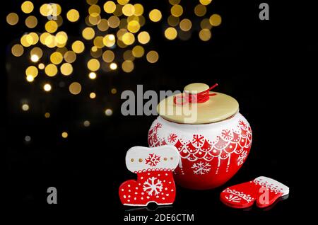 Weihnachtsset mit einem Topf und Holzverzierungen in rot, auf schwarzem Hintergrund mit Bokeh Stockfoto