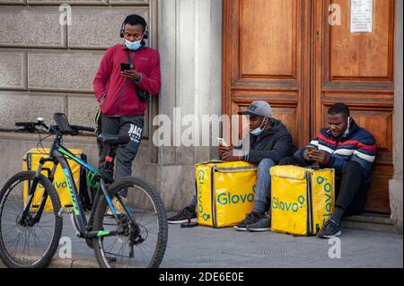Florenz, Italien - 2020. November 19: Fahrer stehen auf der Straße, bereit, Essen in der Stadt zu liefern, während Covid-19 Lockdown. Afrikanischer junger Mann. Stockfoto