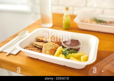 Gesunde leckere Dessert von Pfannkuchen mit Schokoladenpudding und in Scheiben geschnitten Obst im Takeaway-Behälter Stockfoto