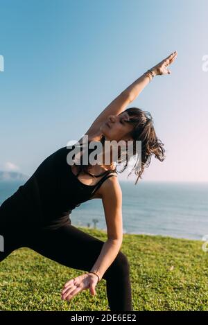 Porträt einer Frau in schwarz gekleidet im Freien praktiziert Yoga. Speicherplatz kopieren Stockfoto