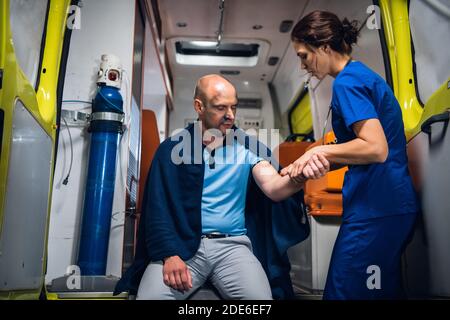 Eine junge Ärztein überprüft die traumatisierte Hand ihrer Patientin in einem Krankenwagen. Stockfoto