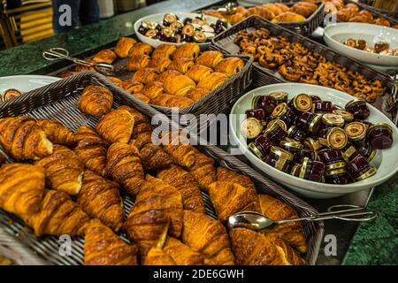 Croissants und verschiedene goldgelbackene Gebäckstücke liegen in Körben auf dem Frühstücksbuffet des Pont Aven von Brittany Ferries, neben Schüsseln mit kleinen Marmeladengläsern. Stockfoto