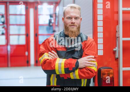 Entschlossener junger Feuerwehrmann vor einem Feuerwehrauto Stockfoto