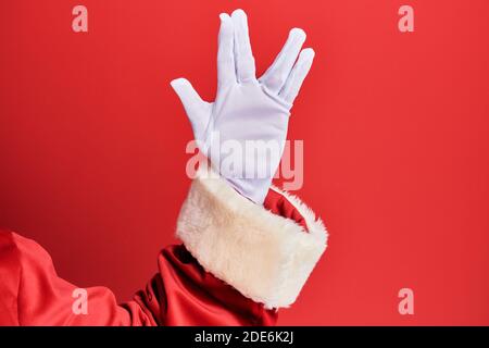 Hand eines Mannes mit weihnachtsmann Kostüm und Handschuhe über rotem Hintergrund Gruß tun vulcan Salute, zeigt Hand Handfläche und Finger, Freak Kultur Stockfoto