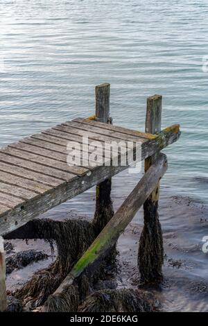 Ein alter hölzerner Steg mit Löchern und verrottenden Planken über dem Meer als Landestatue oder Pier zum Anhängen eines kleinen Bootes. Stockfoto