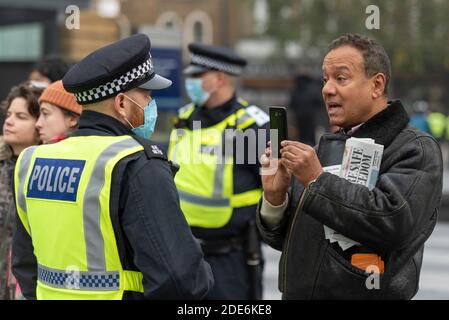 Männlicher Erwachsener streitet mit einem Polizisten, während er ihn bei einem COVID 19 Coronavirus Anti-Lockdown-protestmarsch in London, Großbritannien, aufzeichnete. Handykamera Stockfoto