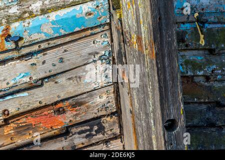 Altes, faules Holzboot mit abblätternder Farbe, die am Ufer aufgewaschen wurde. Stockfoto