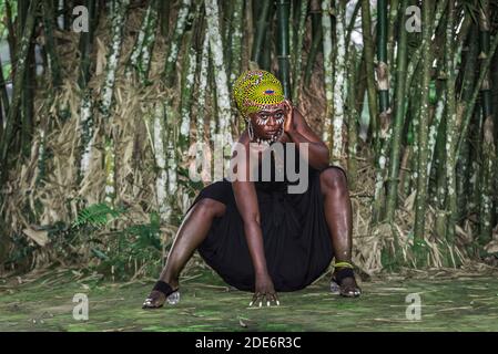 Afrikanische Frau sitzt vor Bambuswald mit Afrikaner Gesichtsbemalung in Aburi Ghana Westafrika Stockfoto