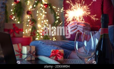 Weihnachten online Familie greetings.Woman hält Sparkler und Champagner in den Händen Wünscht Freunden und Familie Frohe Weihnachten und ein glückliches neues Jahr Per Video Stockfoto