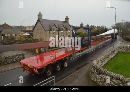 Ein Rotorblatt wird auf einem extra langen LKW zur Lieferung an den Windpark Gordonbush transportiert, wie auf der A9 in Golspie, schottische Highlands, zu sehen ist. Stockfoto