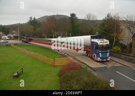 Ein LKW, der ein Turbinenblatt für einen Windpark transportiert Die Verhandlung einer Kurve auf der Straße durch das Dorf von Golspie in den schottischen Highlands Stockfoto