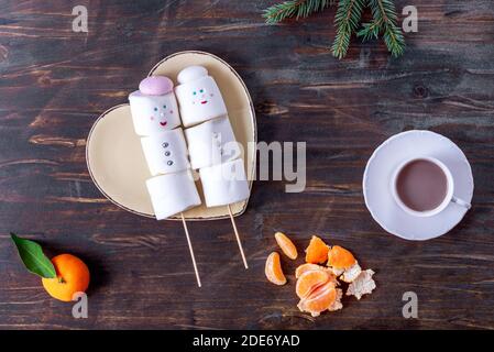 Niedliche Marshmallow Schneemänner auf dem herzförmigen Teller Stockfoto