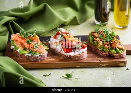 Auswahl an leckeren Bruschetta oder Canapes auf taosted Baguette und Quark Käse mit geräuchertem Lachs, Oliven, Tomaten und Chorizo Wurst gekrönt Stockfoto