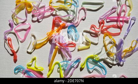 Gruppe von kleinen mehrfarbigen elastischen Bändern für die Haare auf einem weißen Tisch. Stockfoto