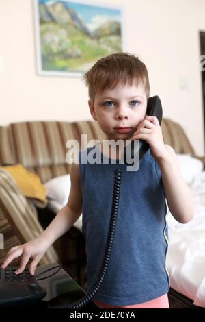 Junge mit Festnetztelefon im Hotelzimmer Stockfoto