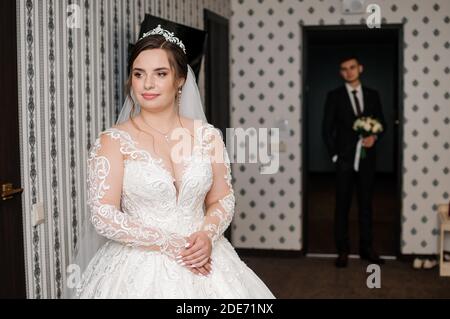 Der Bräutigam trifft die Braut und gibt einen Strauß Blumen im Hotelzimmer Stockfoto