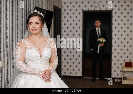 Der Bräutigam trifft die Braut und gibt einen Strauß Blumen im Hotelzimmer Stockfoto