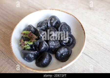 Schwarze Knödel gefüllt mit Fisch im Restaurant Stockfoto