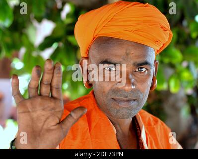 Der Turbaned Gorakhnathi (Kanphata) Yogi Mönch trägt die großen Signaturohrringe des religiösen Gorakh-Nath-Ordens, hebt seine rechte Hand und gibt einen Segen. Stockfoto